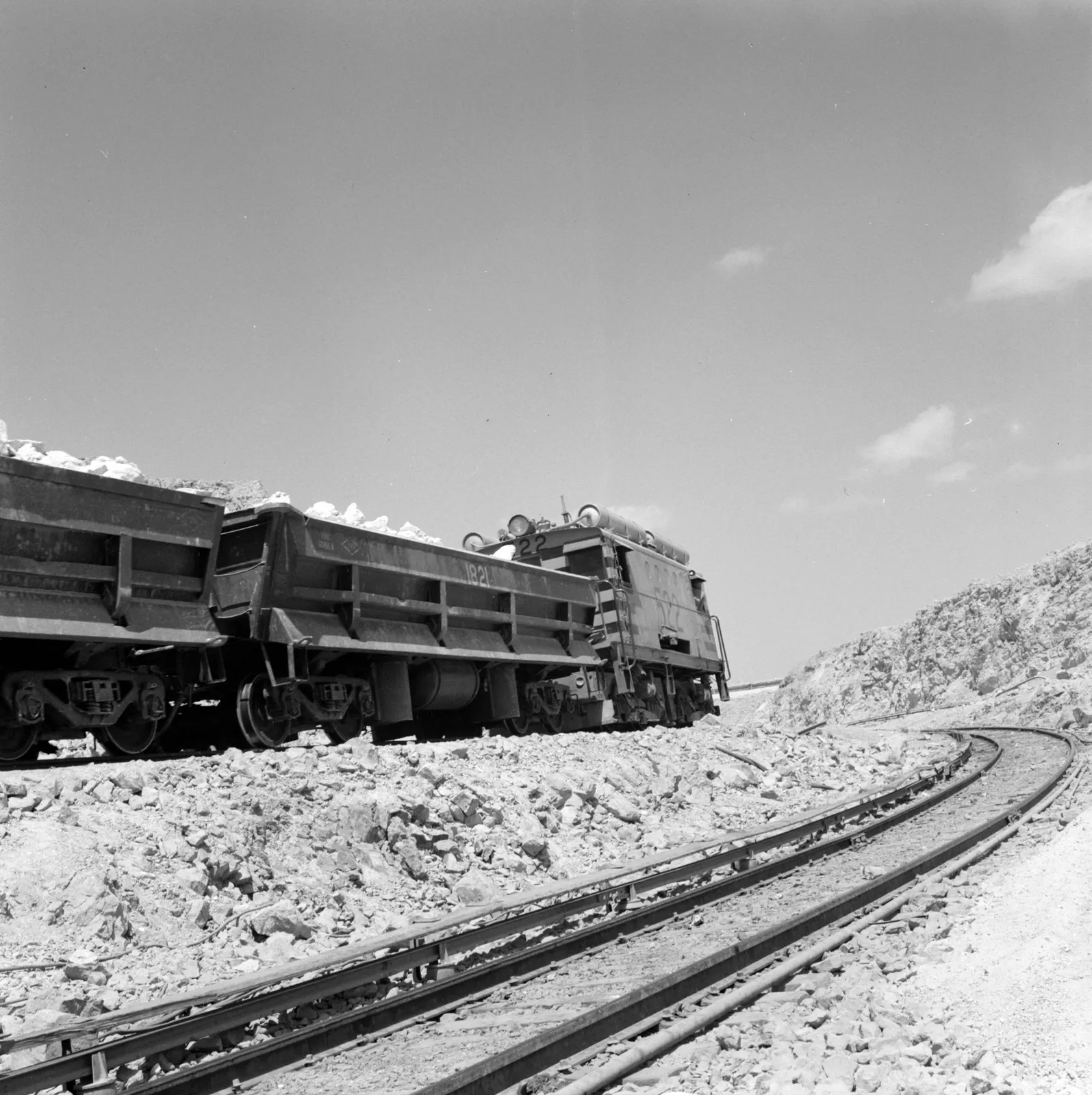Vista de locomotora tirando de vagones en la mina Maria Elena ca. 1960.