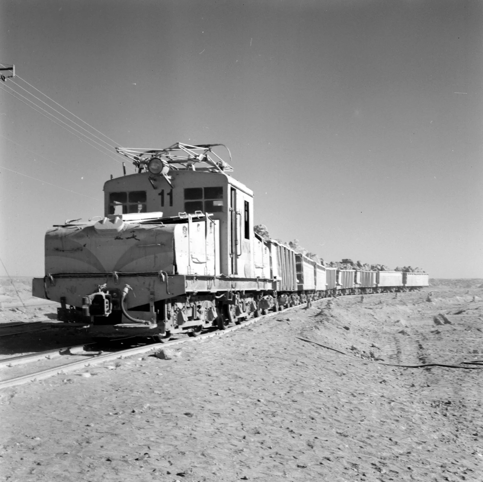 Vista de locomotora tirando de vagones en la mina Maria Elena ca. 1960.