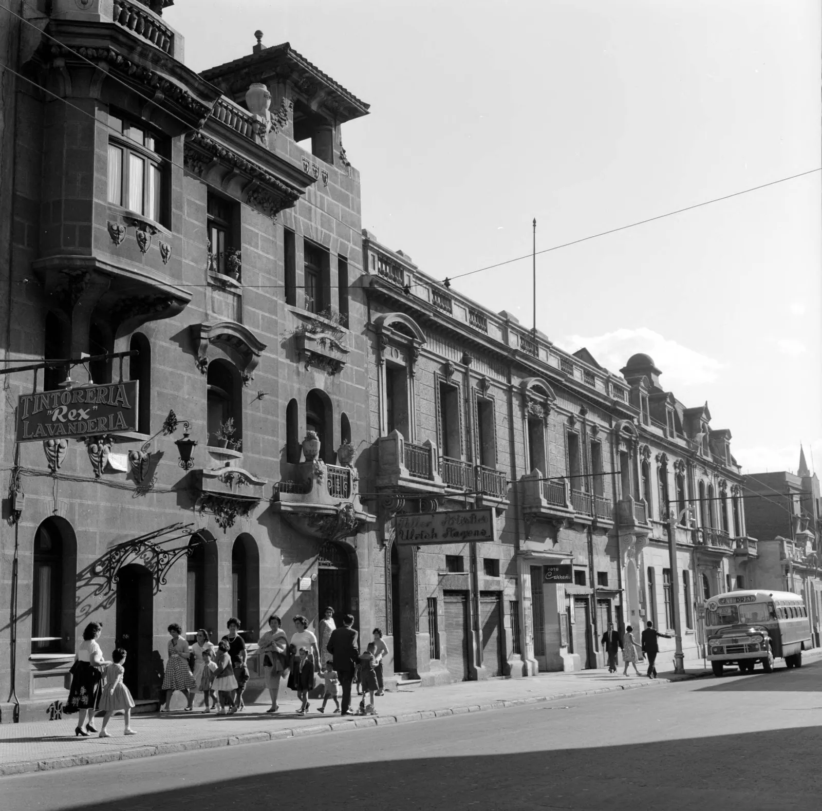 Peatones en la acera junto a tiendas en Santiago ca. 1960.