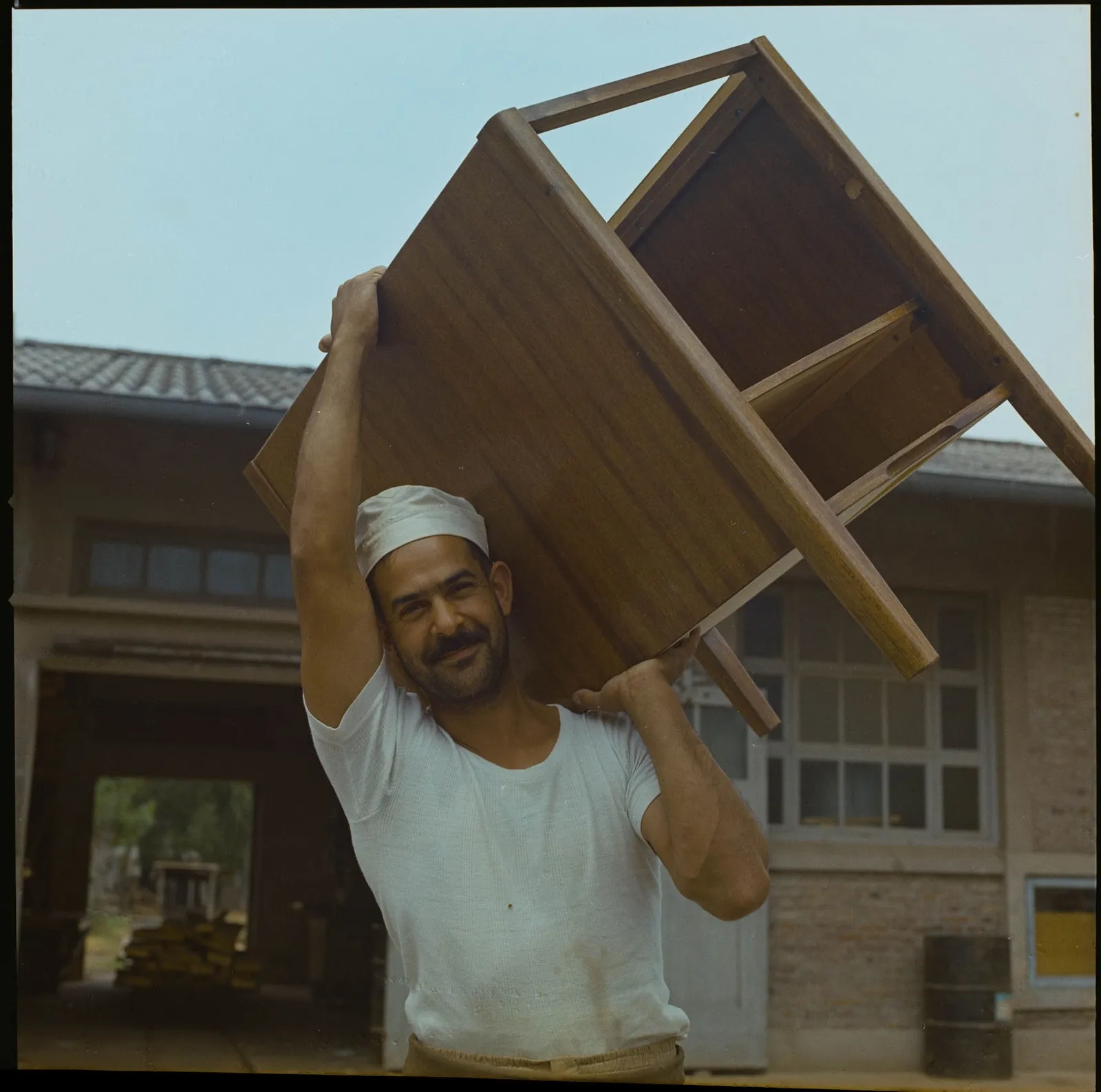 Hombre cargando un mueble de madera, 1964