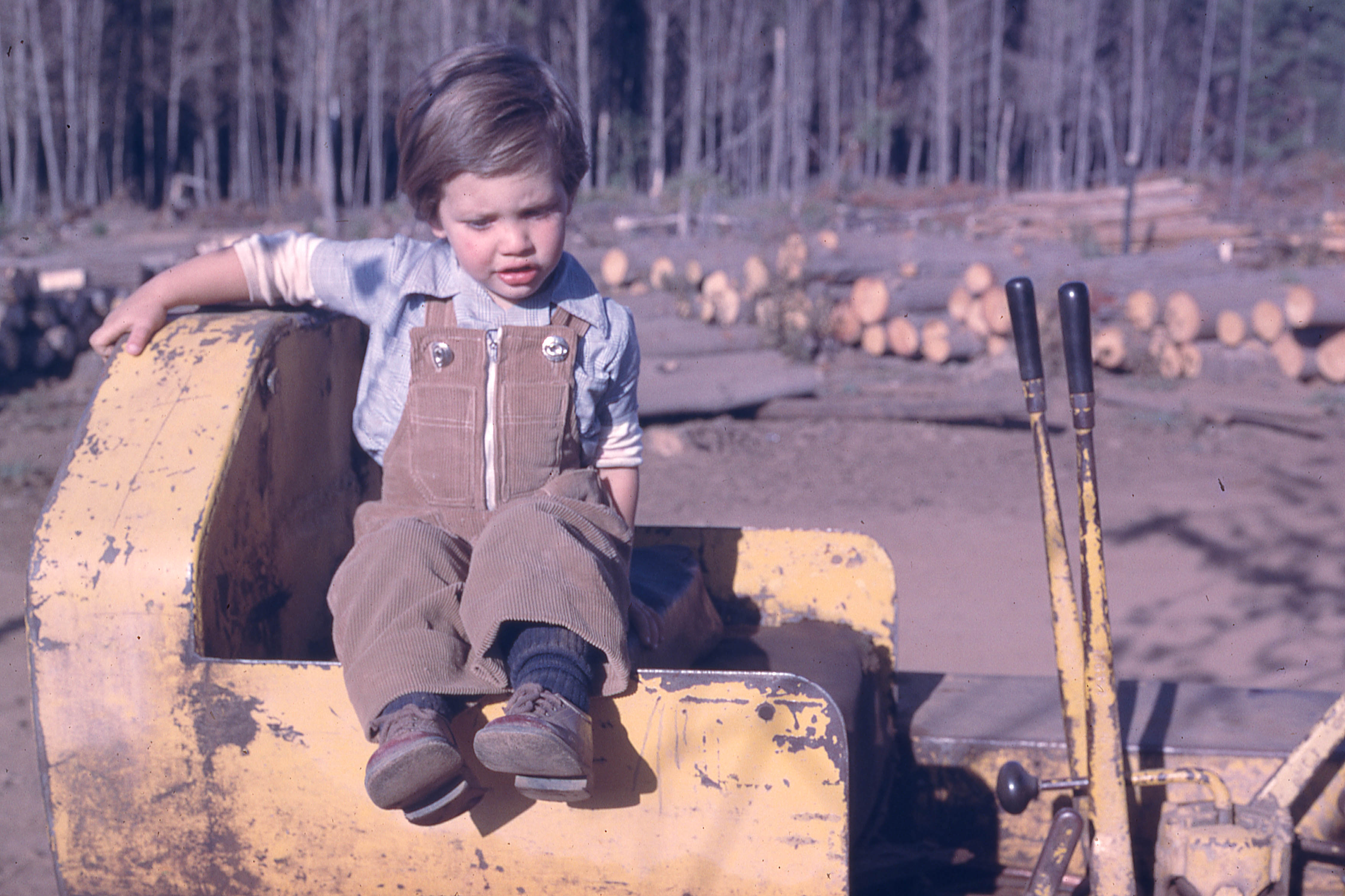 Niño sentado en maquinaria forestal, 1975